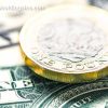 A close-up of British one pound coins, and American one dollar notes.