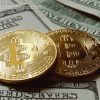 Khmelnitsky, Ukraine - August 02, 2017: Two symbolic coins of bitcoin on banknotes of one hundred dollars. Exchange bitcoin cash for a dollar.